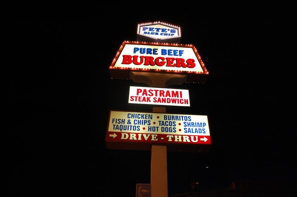 Pete&rsquo;s Blue Chip vintage roadside sign lit up at night: Pure Beef Burgers, Pastrami Steak Sandwich, Drive-Thru